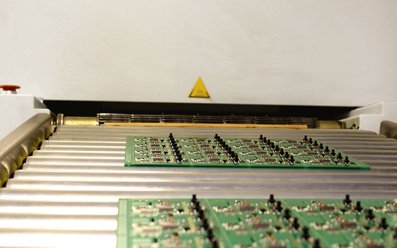 Circuit boards on a conveyer coming out of an oven